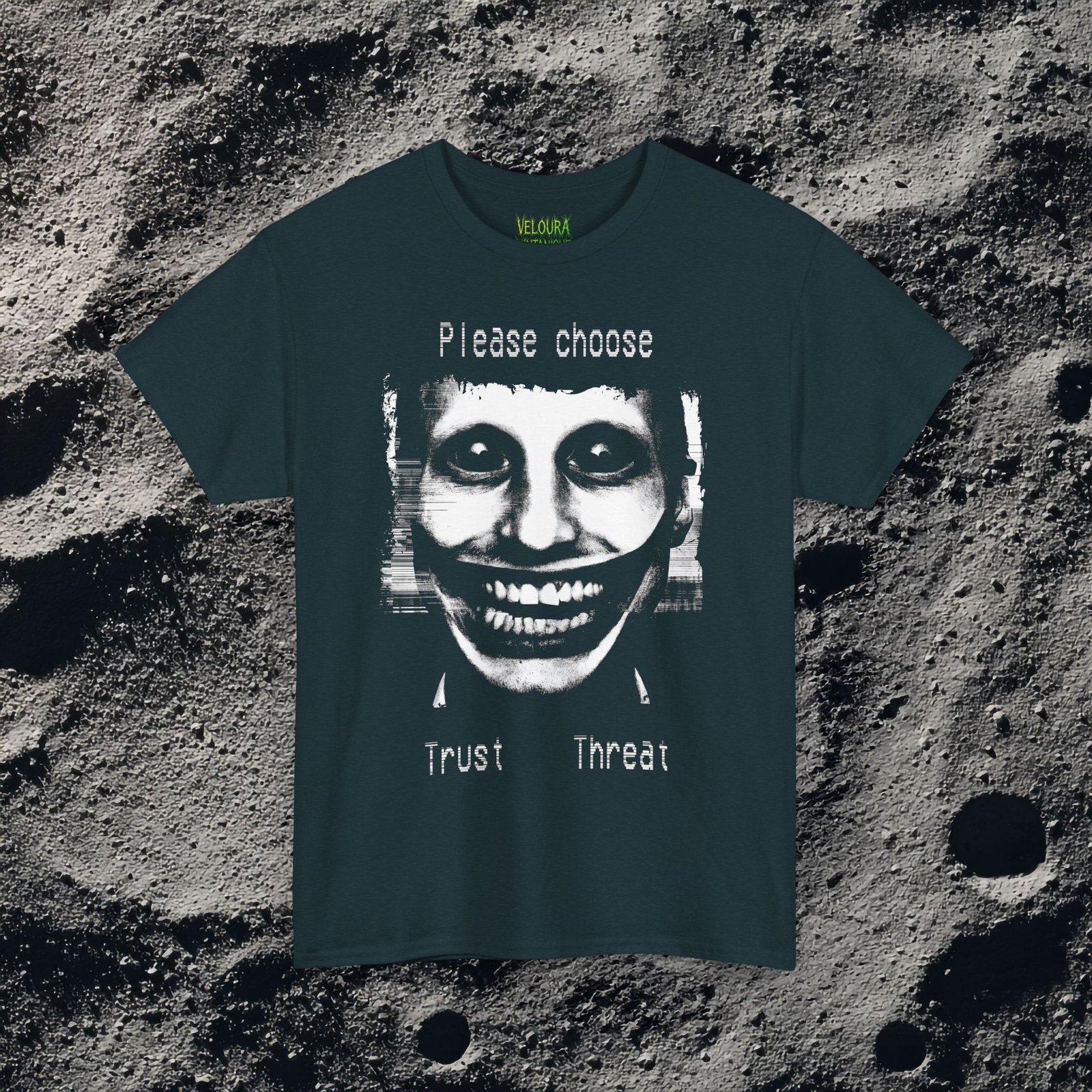 This t-shirt features a disturbing analog horror design of a grinning distorted face in black and white, wide staring eyes, unnaturally stretched mouth filled with teeth, glitch effects across the image. Above the figure is the phrase "Please choose," and below are the words "Trust" and "Threat," giving the design a psychological horror aesthetic that feels like a warning from a cursed VHS tape.