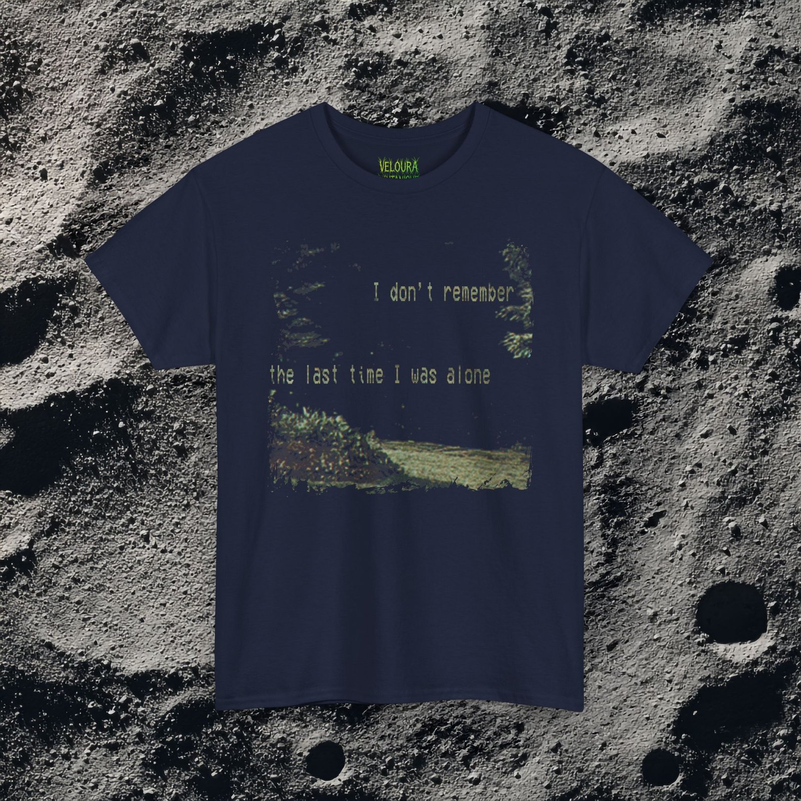 t-shirt features a haunting analog horror design, with the front displaying eerie VHS-style forest imagery and glitch effects alongside the unsettling text “I don’t remember the last time I was alone,” while the back shows a grainy night scene of tall grass and trees with a distorted, skeletal humanoid creature leaning forward and staring with a wide grin, accompanied by the chilling phrase “It never lets me out of sight,” creating a disturbing and atmospheric look that captures the feeling of being stalked and never truly alone.