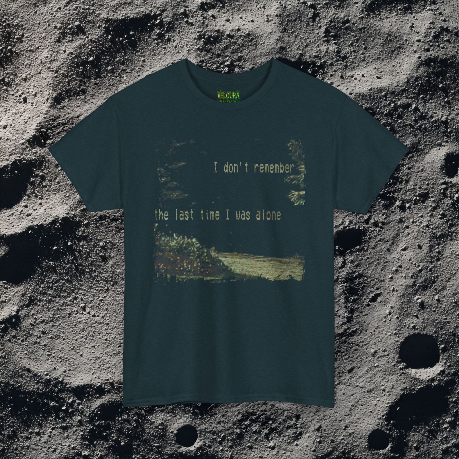 t-shirt features a haunting analog horror design, with the front displaying eerie VHS-style forest imagery and glitch effects alongside the unsettling text “I don’t remember the last time I was alone,” while the back shows a grainy night scene of tall grass and trees with a distorted, skeletal humanoid creature leaning forward and staring with a wide grin, accompanied by the chilling phrase “It never lets me out of sight,” creating a disturbing and atmospheric look that captures the feeling of being stalked and never truly alone.
