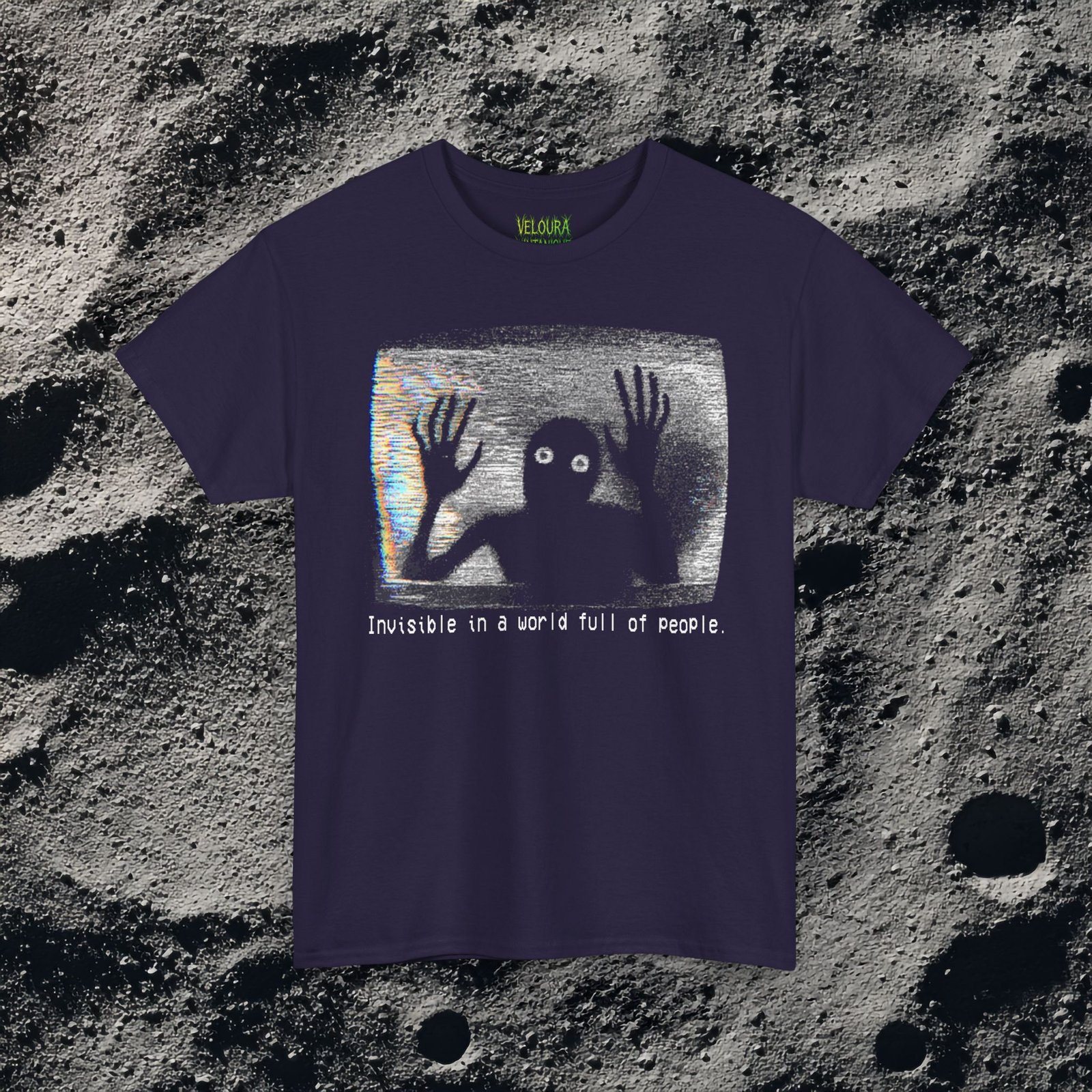 This black T-shirt features an analog horror inspired design of a grainy, distorted humanoid silhouette trapped inside a static-filled television screen. The shadowy figure presses its long, bony hands against the glass as if trying to escape, while its glowing white eyes stare outward in a mix of fear and desperation. VHS-style static and rainbow glitch streaks fill the background, giving the design the appearance of a corrupted video frame. Beneath the image, in a pixelated glitch font, the text reads “Invisible in a world full of people,” adding a dark, emotional layer of loneliness and isolation to the already unsettling graphic.