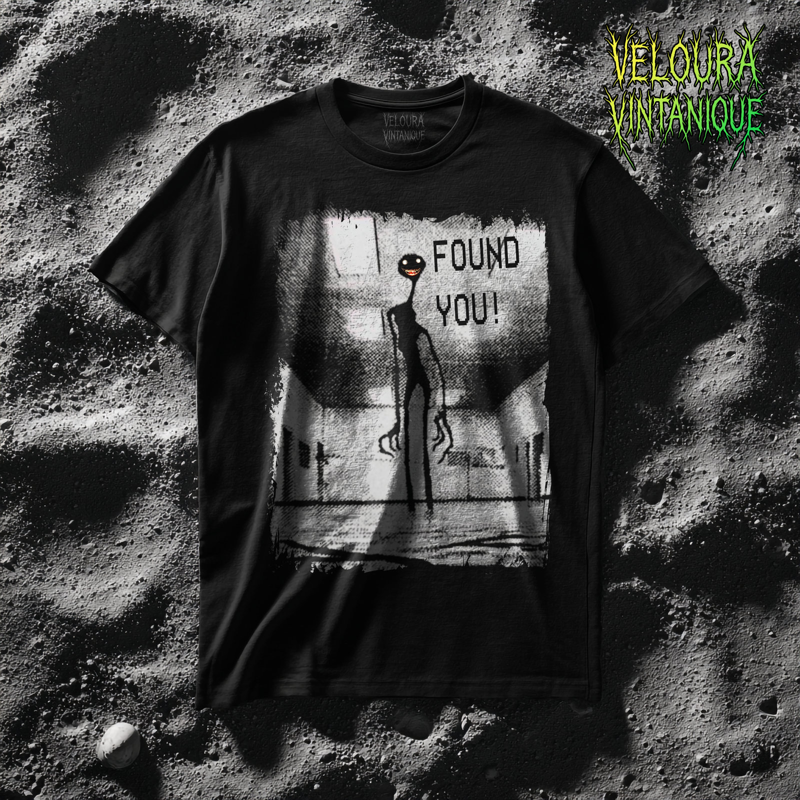 A grainy black-and-white analog-horror print shows a long-limbed, towering figure in a fluorescent-lit corridor, its tiny round eyes glowing and a sharp, cartoonish grin shining in the gloom; the scene has rough, distressed edges and VHS-style halftone texture, and the words “FOUND YOU!” sit near the creature’s head, turning the hallway image into a creepy liminal encounter.The classic fit of this shirt ensures a comfy, relaxed wear while the crew neckline adds that neat, timeless look that can blend into any occasion, casual or semi-formal. Made using 100% US cotton that is ethically grown and harvested.