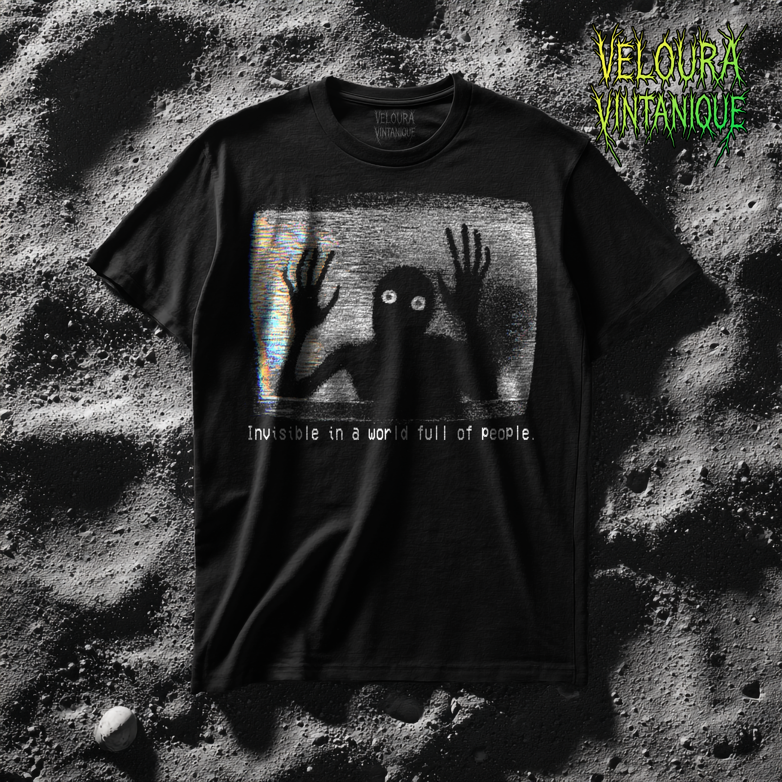 This black T-shirt features an analog horror inspired design of a grainy, distorted humanoid silhouette trapped inside a static-filled television screen. The shadowy figure presses its long, bony hands against the glass as if trying to escape, while its glowing white eyes stare outward in a mix of fear and desperation. VHS-style static and rainbow glitch streaks fill the background, giving the design the appearance of a corrupted video frame. Beneath the image, in a pixelated glitch font, the text reads “Invisible in a world full of people,” adding a dark, emotional layer of loneliness and isolation to the already unsettling graphic.