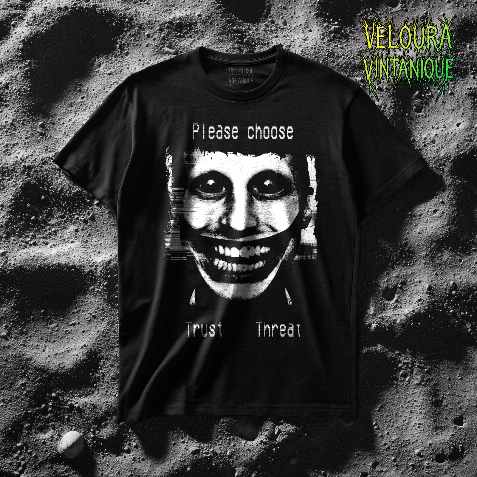 This t-shirt features a disturbing analog horror design of a grinning distorted face in black and white, wide staring eyes, unnaturally stretched mouth filled with teeth, glitch effects across the image. Above the figure is the phrase "Please choose," and below are the words "Trust" and "Threat," giving the design a psychological horror aesthetic that feels like a warning from a cursed VHS tape.