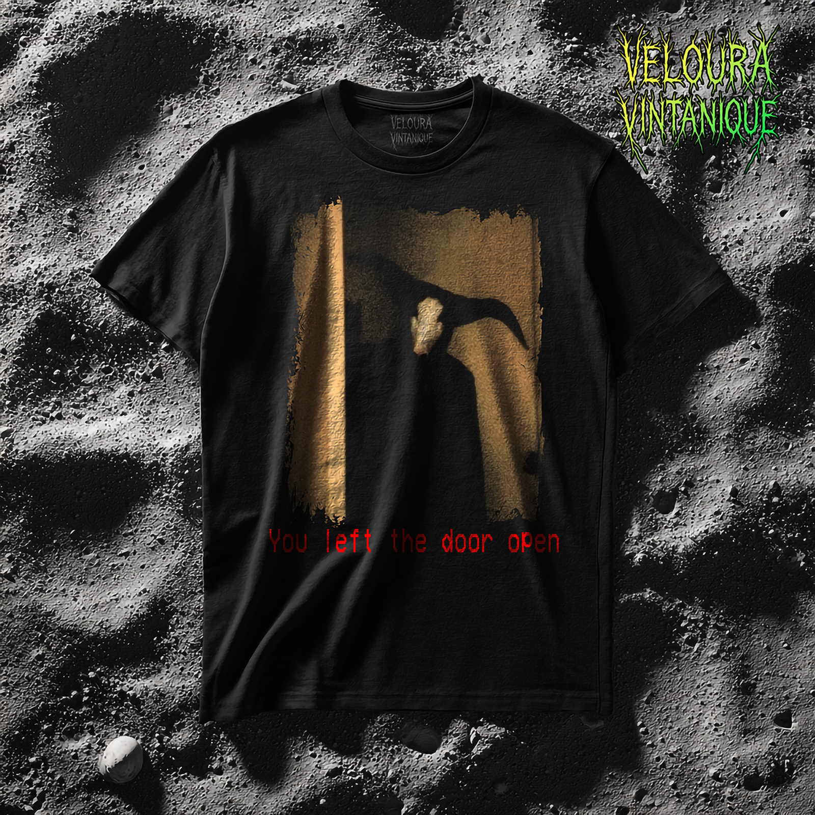 This t-shirt features a haunting analog horror style design showing a dark, shadowy horned figure lurking in a dimly lit doorway, its head resembling a pale skull-like mask while its large twisted horns stretch out into the room, all presented with a grainy, distressed texture that enhances the eerie VHS aesthetic; beneath the image, in unsettling blood-red glitchy letters, the phrase “You left the door open” is printed, making the shirt feel like a cursed object straight from a nightmare.