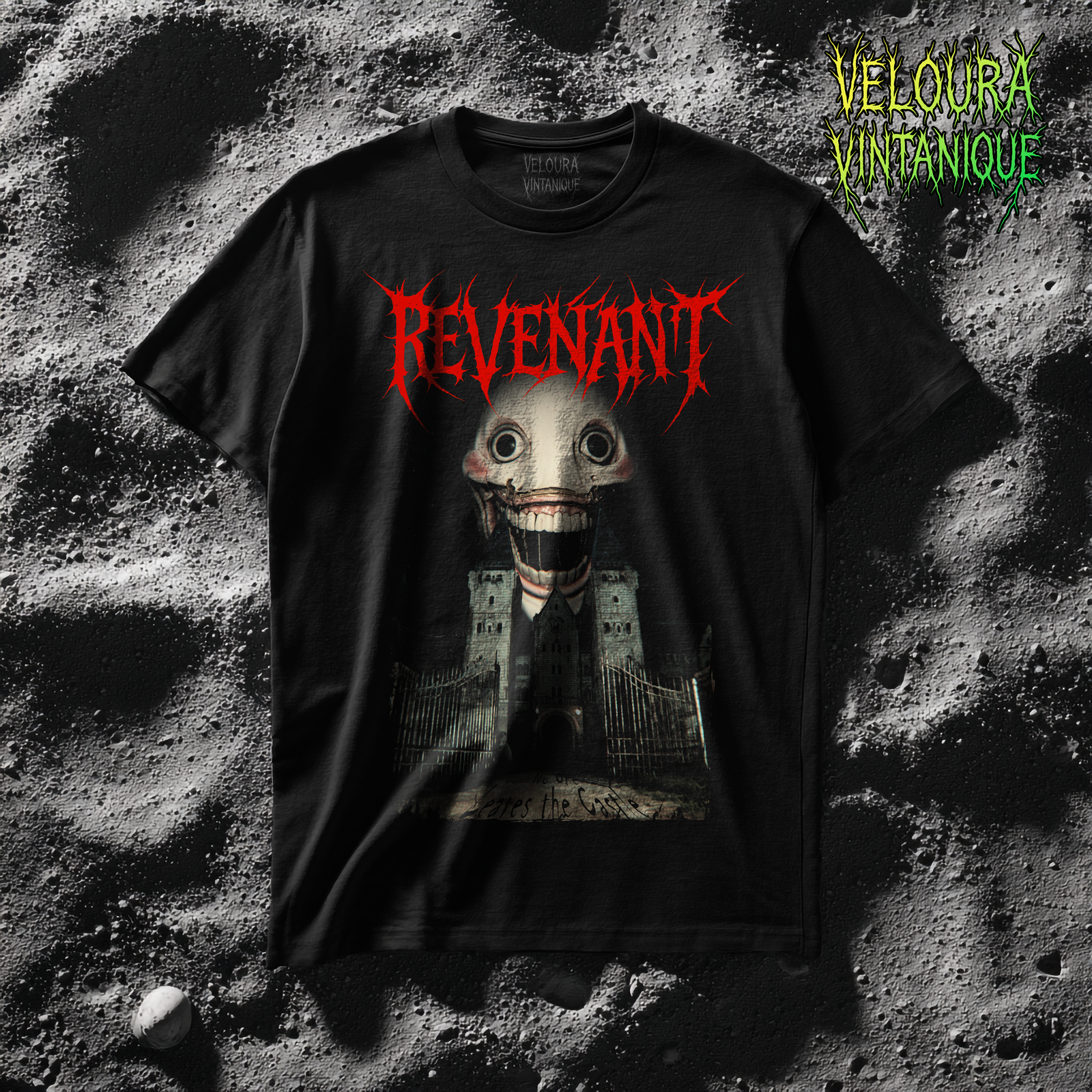 The t-shirt design features a large, jagged red logo at the top spelling “REVENANT” in a spiked, horror-themed font. Below it is a towering, pale creature with a distorted face, huge round eyes, and an unnaturally wide mouth filled with sharp, exaggerated teeth. The creature looms behind an old, abandoned stone castle with multiple towers and dark windows. In front of the castle, a set of tall, rusted metal gates stand partially open, leading toward a cracked and worn pathway. Near the bottom, faint handwritten text appears as though it is scratched into the ground, adding to the eerie and unsettling atmosphere of the design.