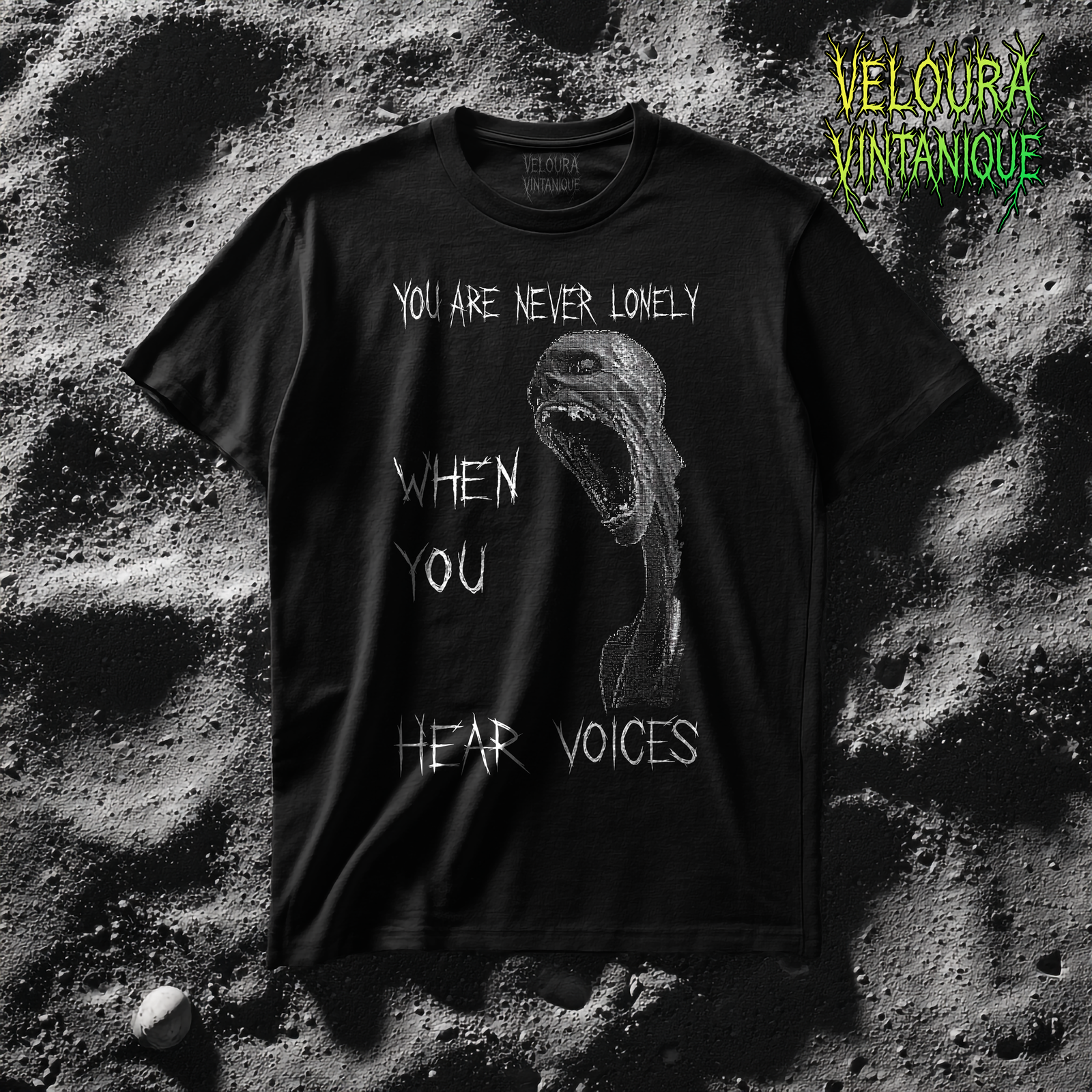 This dark horror T-shirt features a stark black background with a high-contrast, grainy white illustration of a distorted screaming humanoid figure. The unsettling artwork is paired with fragmented, scratchy text reading “You Are Never Lonely When You Hear Voices,” arranged vertically to amplify the uneasy, intrusive tone. The rough, analog-style texture gives the design a raw VHS and underground horror feel. Minimal color, heavy contrast, and psychological tension make this shirt ideal for fans of creepy art, unsettling statements, and dark alternative fashion.