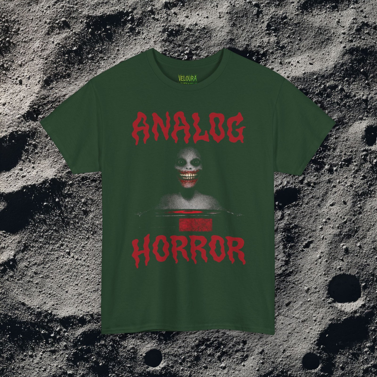 This T-shirt features a disturbing analog horror design with a shadowy smiling figure emerging from darkness, framed by bold dripping red ANALOG HORROR text. The grainy texture, low-contrast lighting, and VHS-style distortion create the feeling of a cursed tape still playing long after it should have stopped. The unsettling grin and minimal color palette amplify the psychological horror aesthetic, making this shirt perfect for fans of analog horror, creepypasta, liminal media, and retro VHS nightmares.