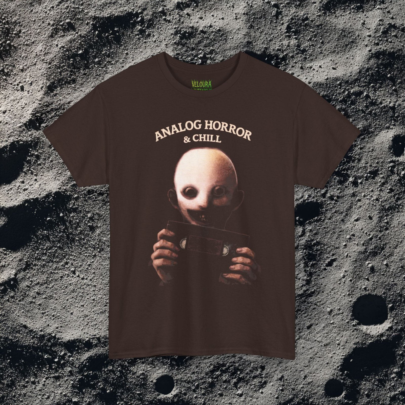 This eerie design features a pale, unsettling figure holding a VHS cassette, paired with the phrase “Analog Horror & Chill.” The dark lighting, grainy textures, and muted tones create a strong analog horror and retro found-footage aesthetic. The character’s hollow eyes and subtle smile add an extra layer of psychological unease, making this design perfect for fans of creepy visuals, weirdcore art, and retro horror culture. A must-have for anyone who loves horror with nostalgic VHS vibes.