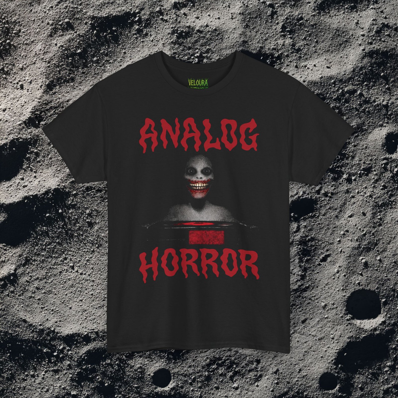 This T-shirt features a disturbing analog horror design with a shadowy smiling figure emerging from darkness, framed by bold dripping red ANALOG HORROR text. The grainy texture, low-contrast lighting, and VHS-style distortion create the feeling of a cursed tape still playing long after it should have stopped. The unsettling grin and minimal color palette amplify the psychological horror aesthetic, making this shirt perfect for fans of analog horror, creepypasta, liminal media, and retro VHS nightmares.