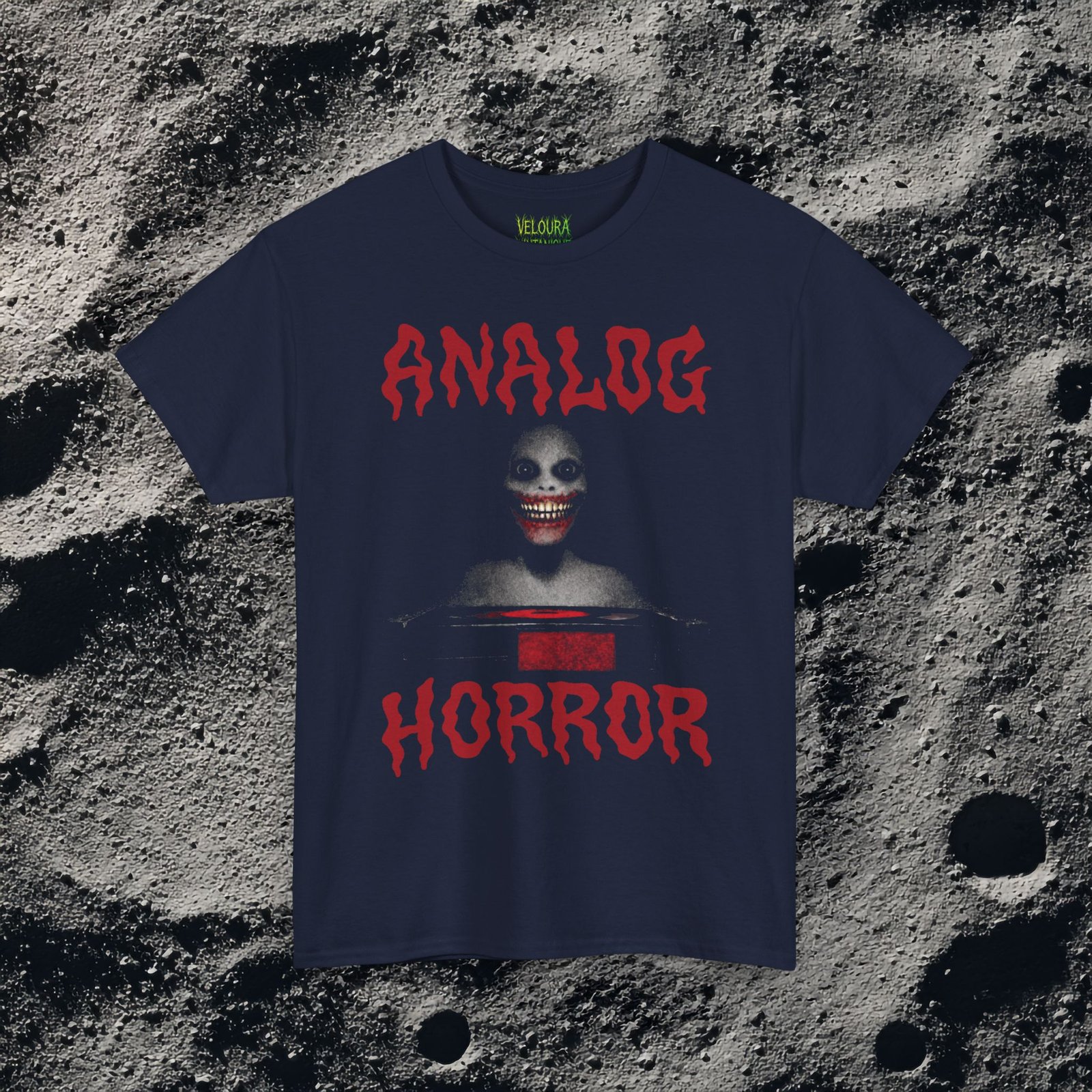 This T-shirt features a disturbing analog horror design with a shadowy smiling figure emerging from darkness, framed by bold dripping red ANALOG HORROR text. The grainy texture, low-contrast lighting, and VHS-style distortion create the feeling of a cursed tape still playing long after it should have stopped. The unsettling grin and minimal color palette amplify the psychological horror aesthetic, making this shirt perfect for fans of analog horror, creepypasta, liminal media, and retro VHS nightmares.