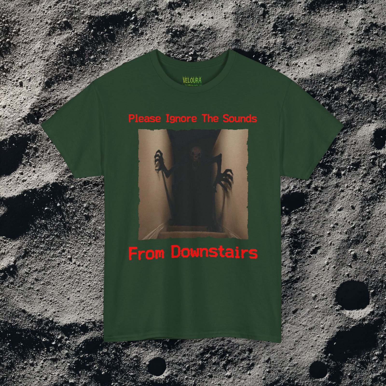 This horror-inspired T-shirt features a terrifying shadow creature crawling up from a dark basement stairwell, framed in dim lighting with an unsettling atmosphere. The bold red text reads, “Please Ignore The Sounds From Downstairs,” adding a disturbing, analog horror tone to the artwork. The creature’s elongated limbs and sharp claws create a nightmarish silhouette that stands out on black fabric. Perfect for horror fans, Halloween lovers, creepy aesthetic enthusiasts, and anyone who enjoys dark, unsettling graphic tees.