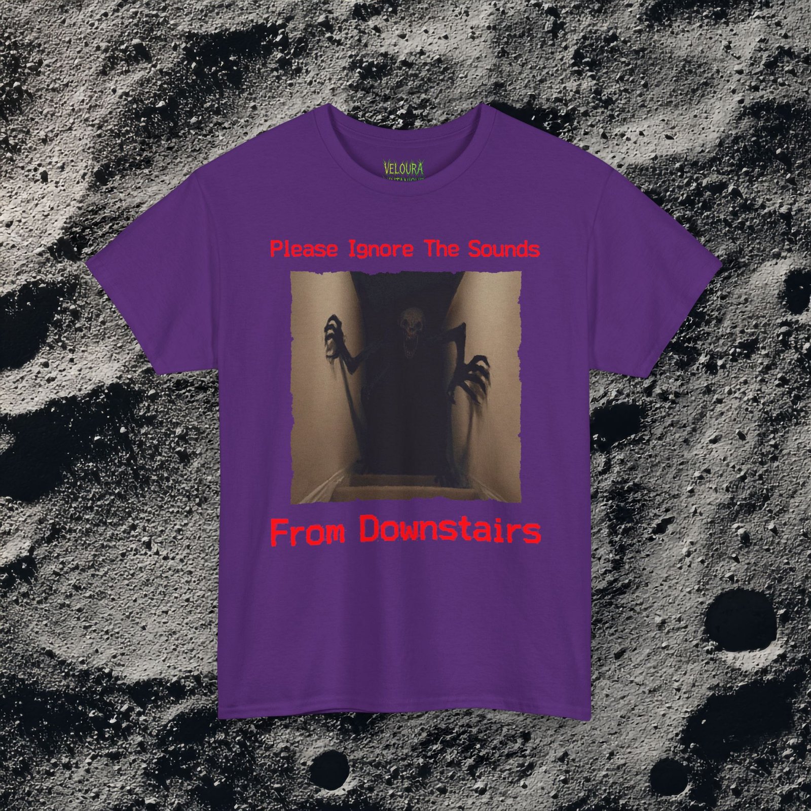 This horror-inspired T-shirt features a terrifying shadow creature crawling up from a dark basement stairwell, framed in dim lighting with an unsettling atmosphere. The bold red text reads, “Please Ignore The Sounds From Downstairs,” adding a disturbing, analog horror tone to the artwork. The creature’s elongated limbs and sharp claws create a nightmarish silhouette that stands out on black fabric. Perfect for horror fans, Halloween lovers, creepy aesthetic enthusiasts, and anyone who enjoys dark, unsettling graphic tees.