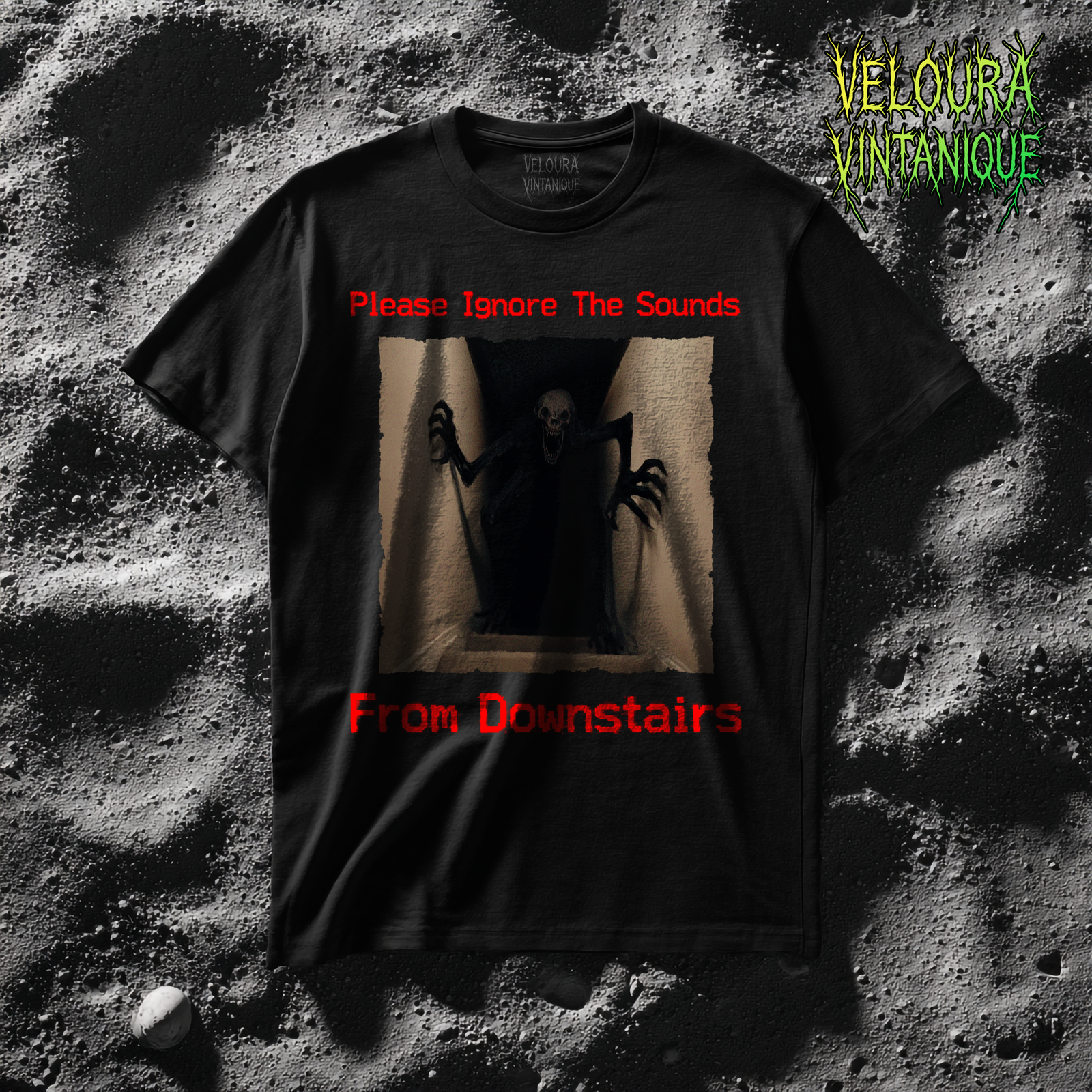 This horror-inspired T-shirt features a terrifying shadow creature crawling up from a dark basement stairwell, framed in dim lighting with an unsettling atmosphere. The bold red text reads, “Please Ignore The Sounds From Downstairs,” adding a disturbing, analog horror tone to the artwork. The creature’s elongated limbs and sharp claws create a nightmarish silhouette that stands out on black fabric. Perfect for horror fans, Halloween lovers, creepy aesthetic enthusiasts, and anyone who enjoys dark, unsettling graphic tees.