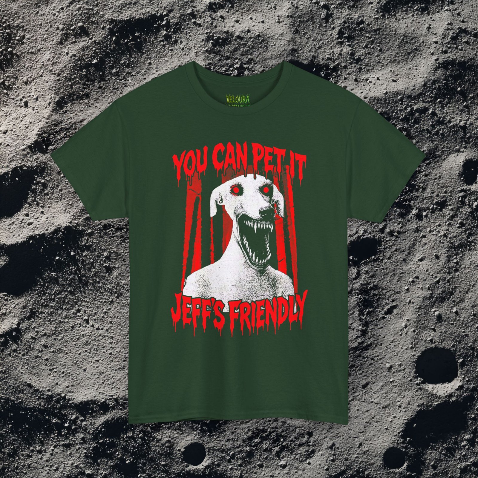 This creepy horror T-shirt features a terrifying dog-like creature with glowing red eyes and a wide mouth full of sharp teeth. The disturbing figure appears against a dark forest background, while dripping red horror-style text reads “YOU CAN PET IT” and “JEFF’S FRIENDLY.” The gritty analog horror art style creates an unsettling atmosphere reminiscent of internet creepypasta and cursed VHS aesthetics. The bold red and black contrast gives the design a striking and sinister look.