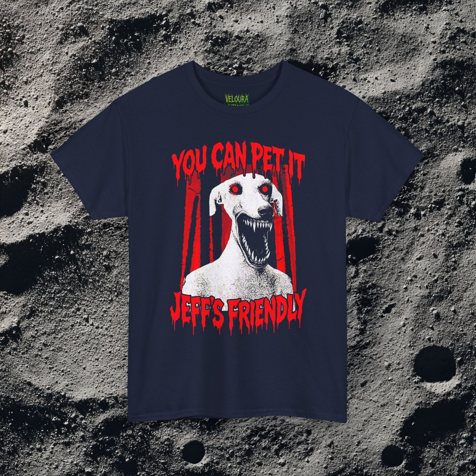 This creepy horror T-shirt features a terrifying dog-like creature with glowing red eyes and a wide mouth full of sharp teeth. The disturbing figure appears against a dark forest background, while dripping red horror-style text reads “YOU CAN PET IT” and “JEFF’S FRIENDLY.” The gritty analog horror art style creates an unsettling atmosphere reminiscent of internet creepypasta and cursed VHS aesthetics. The bold red and black contrast gives the design a striking and sinister look.
