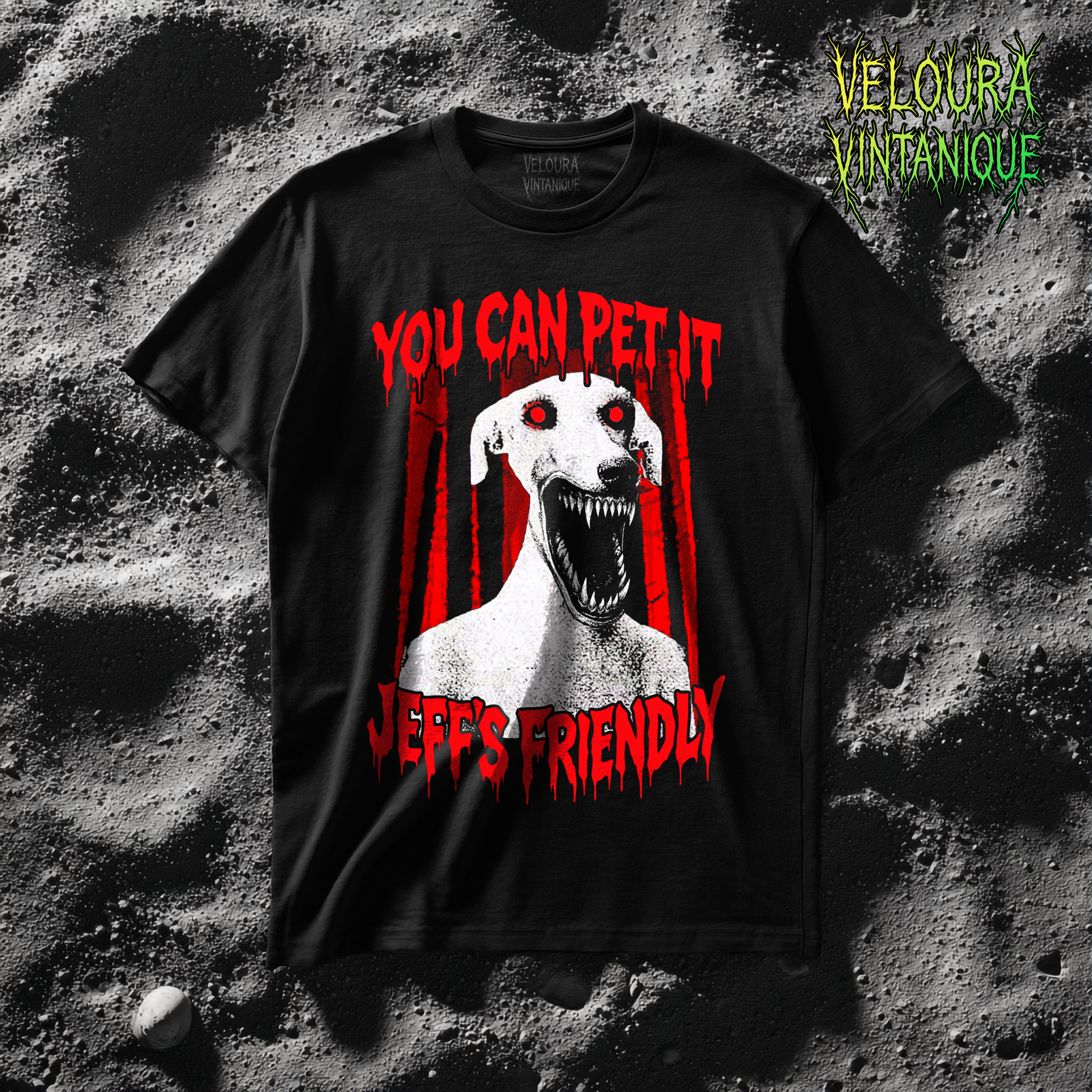This creepy horror T-shirt features a terrifying dog-like creature with glowing red eyes and a wide mouth full of sharp teeth. The disturbing figure appears against a dark forest background, while dripping red horror-style text reads “YOU CAN PET IT” and “JEFF’S FRIENDLY.” The gritty analog horror art style creates an unsettling atmosphere reminiscent of internet creepypasta and cursed VHS aesthetics. The bold red and black contrast gives the design a striking and sinister look.